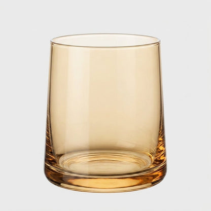 Single amber translucent drinking glass on a light gray background
