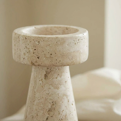 Close-up of a cream travertine pillar candleholder showing its pitted natural stone texture