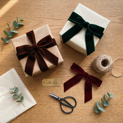 Velvet bows with gift wrapping supplies on wooden table