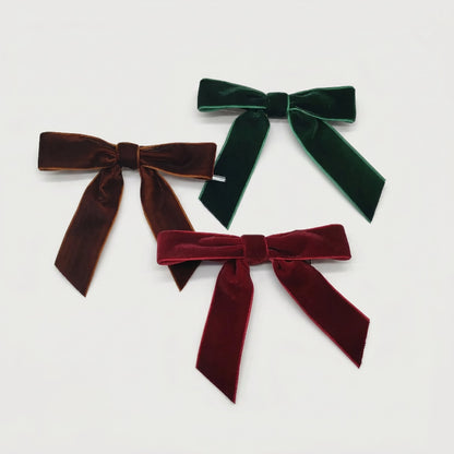 Velvet bows in burgundy, green, and brown on white background