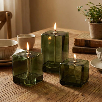 Three green glass candles on a wooden table with a warm ambiance.