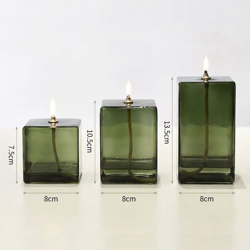 Three green glass candle holders with lit candles, shown with measurements on a white background.