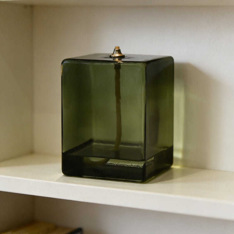 Green glass cube on a white shelf with a neutral background