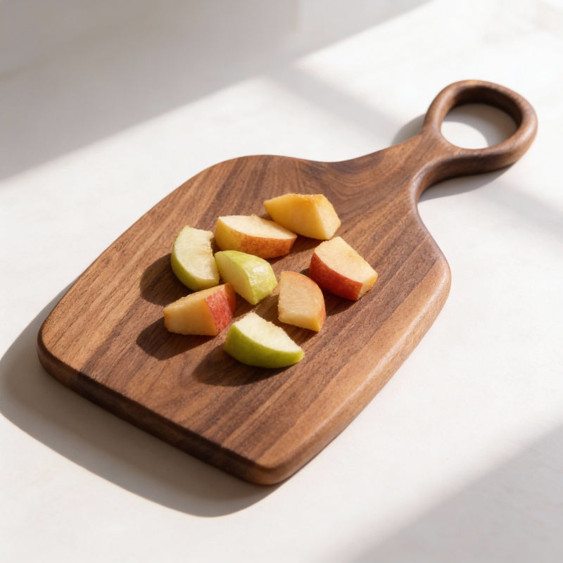 Wooden cutting board with sliced apples on a white surface