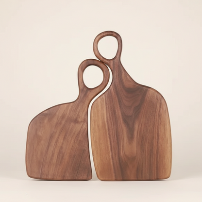 Two wooden cutting boards with handles on a beige background