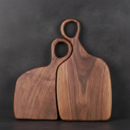 Two wooden cutting boards with handles on a dark background