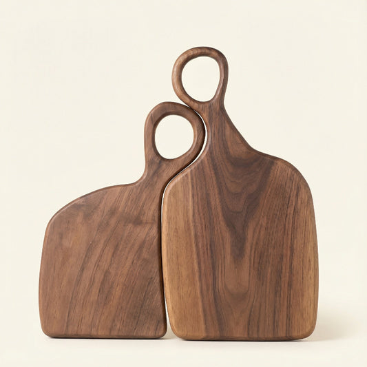 Two wooden cutting boards with handles on a beige background