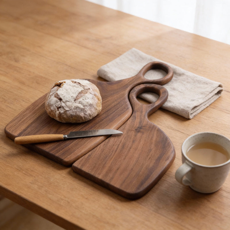 Wooden cutting board with bread and knife on a wooden table with a cup of tea.