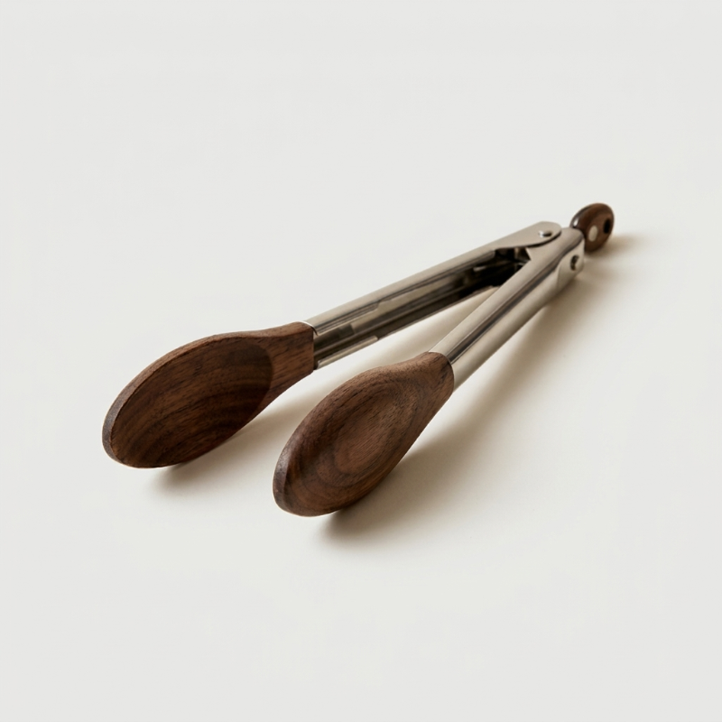 Stainless steel and wood tongs on white background facing left