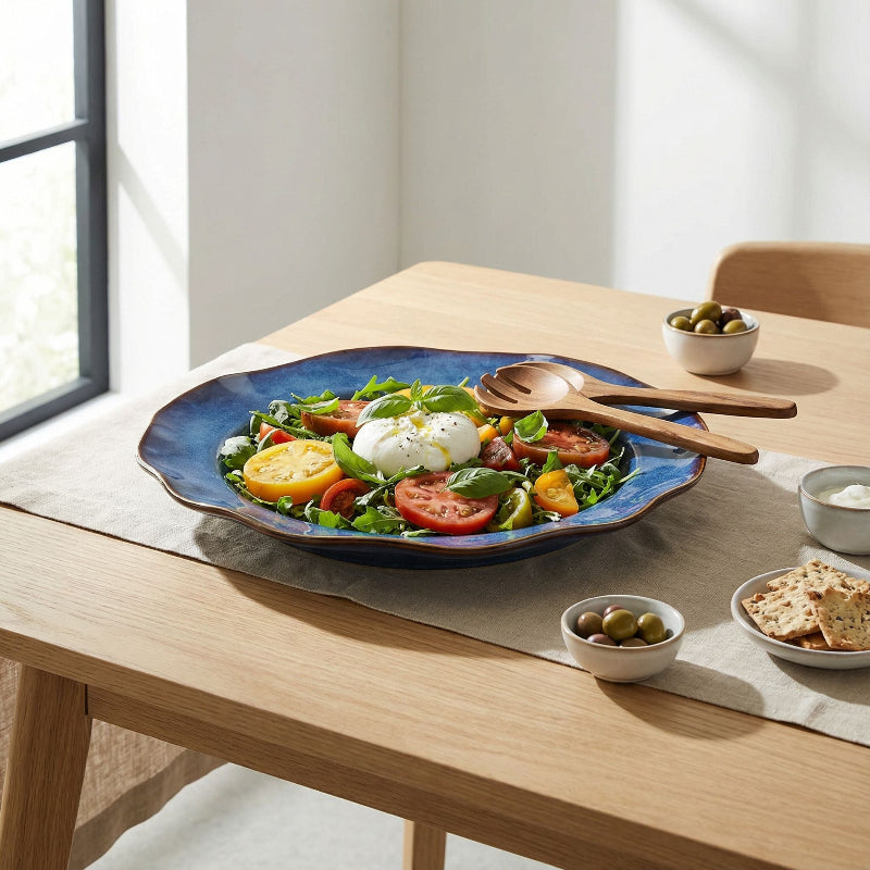 Salad on a blue plate with wooden utensils on a wooden table