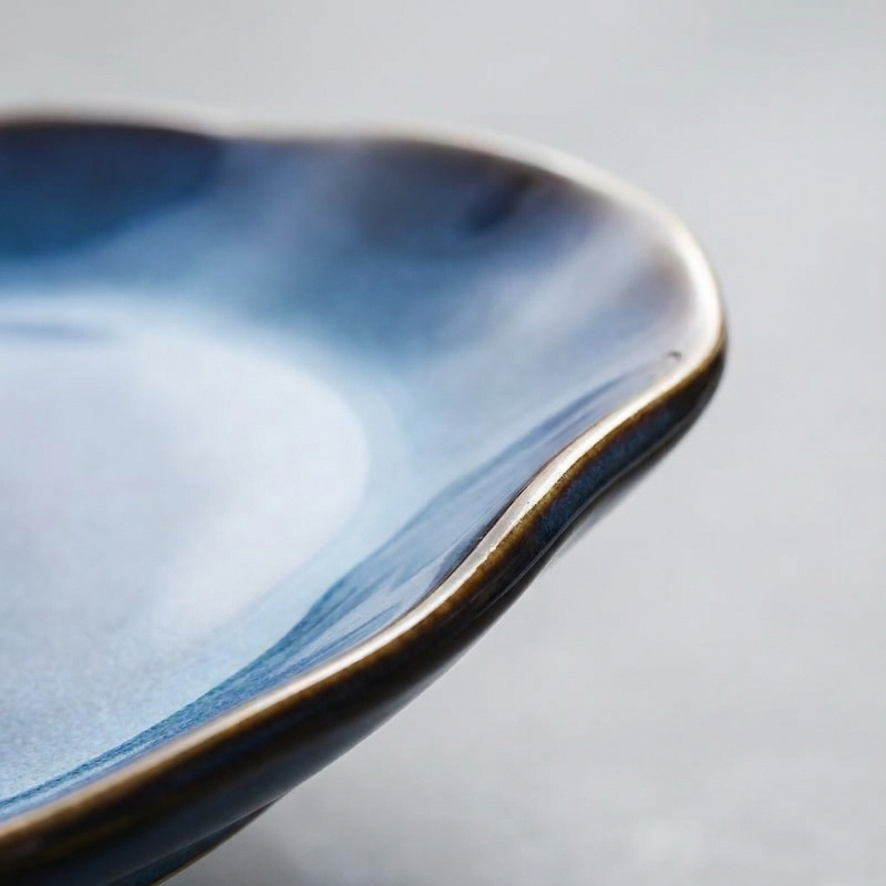 Close-up of a ceramic dish with blue glaze on a gray background