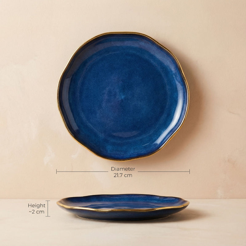 Blue ceramic plate with gold rim on a beige background, showing measurements.
