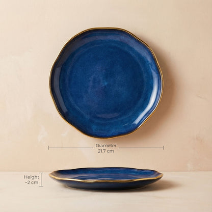 Blue ceramic plate with gold rim on a beige background, showing measurements.