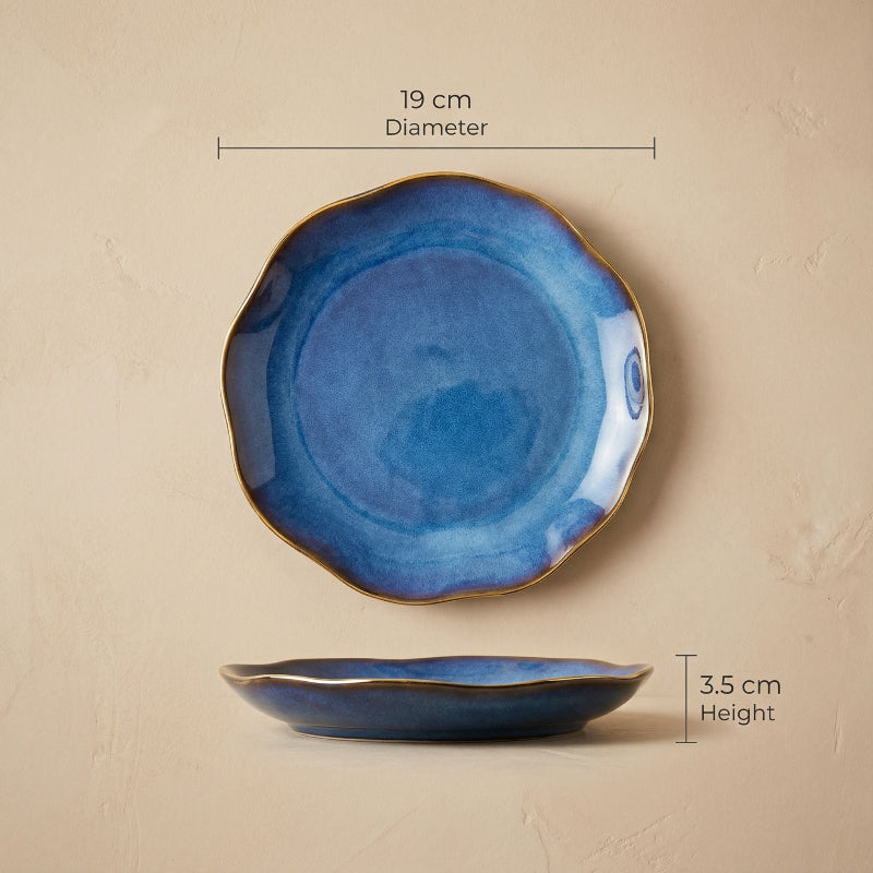 Blue ceramic plate with gold rim and measurements on a beige background