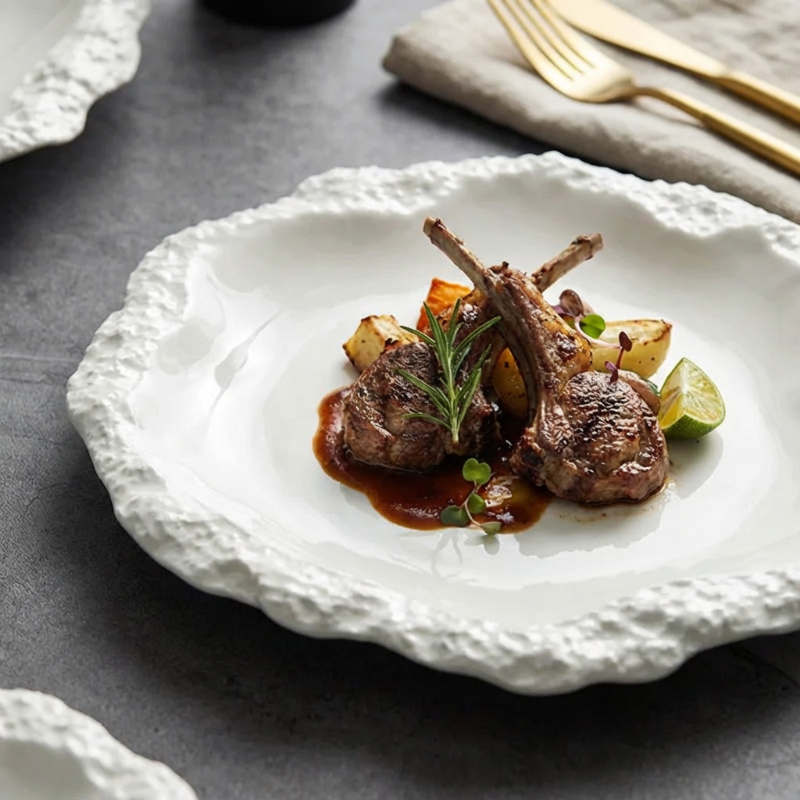 Lamb chops with potatoes and herbs on a decorative white plate.