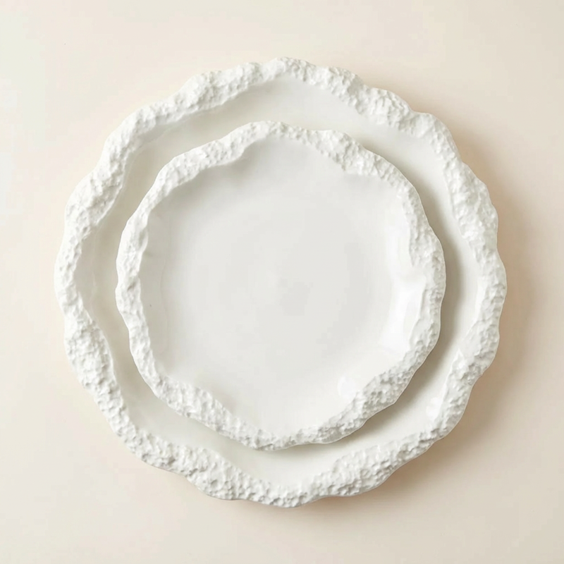Set of three white decorative plates with textured edges on a beige background