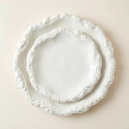 Set of three white decorative plates with textured edges on a beige background