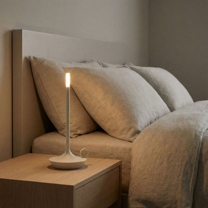 Lamp on a nightstand next to a bed with pillows