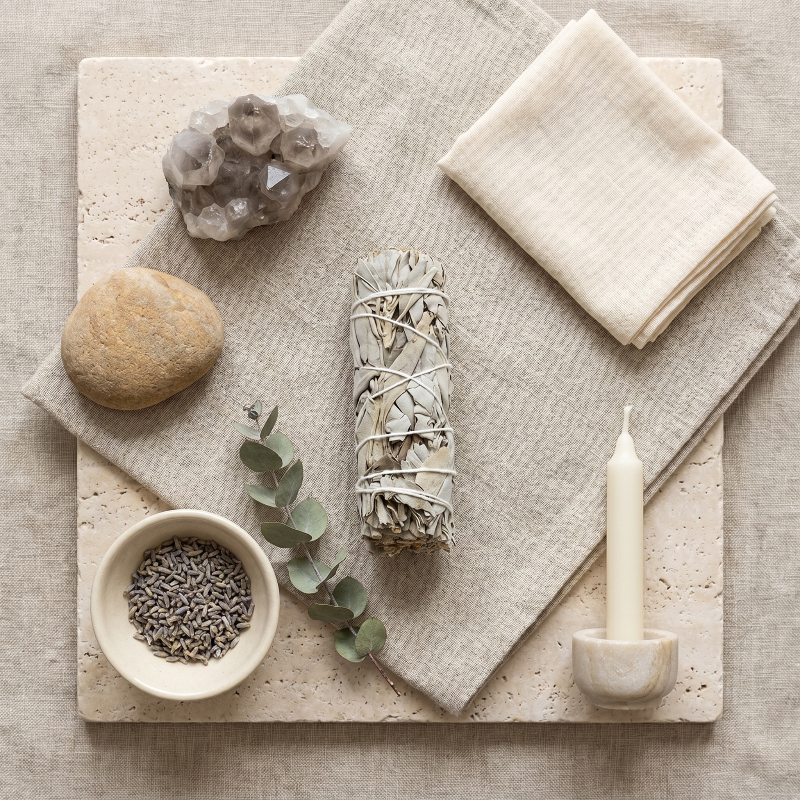 White sage smudge bundle with cleansing ritual tools on neutral surface