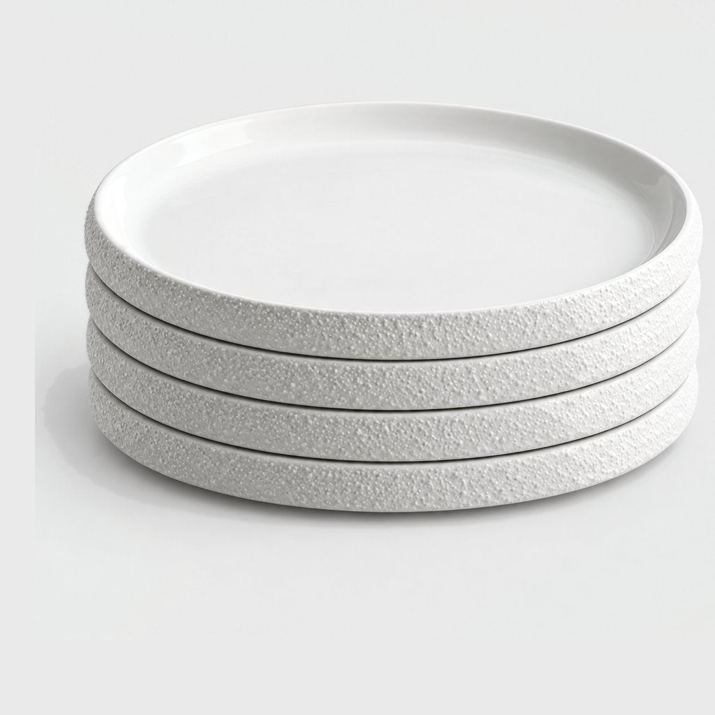Stack of four large white textured ceramic plates on a plain light background