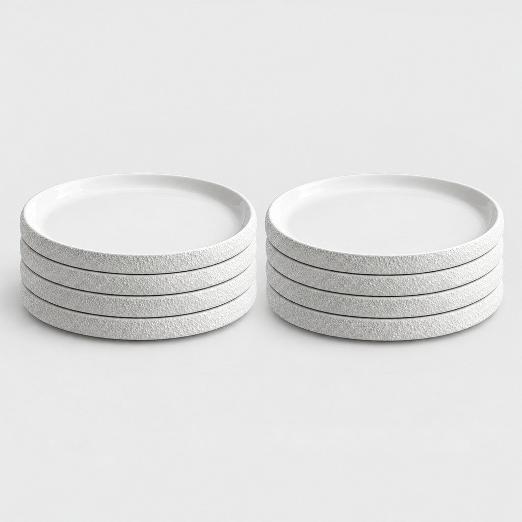 Two stacks of four white textured ceramic plates in two sizes side by side on a plain light background