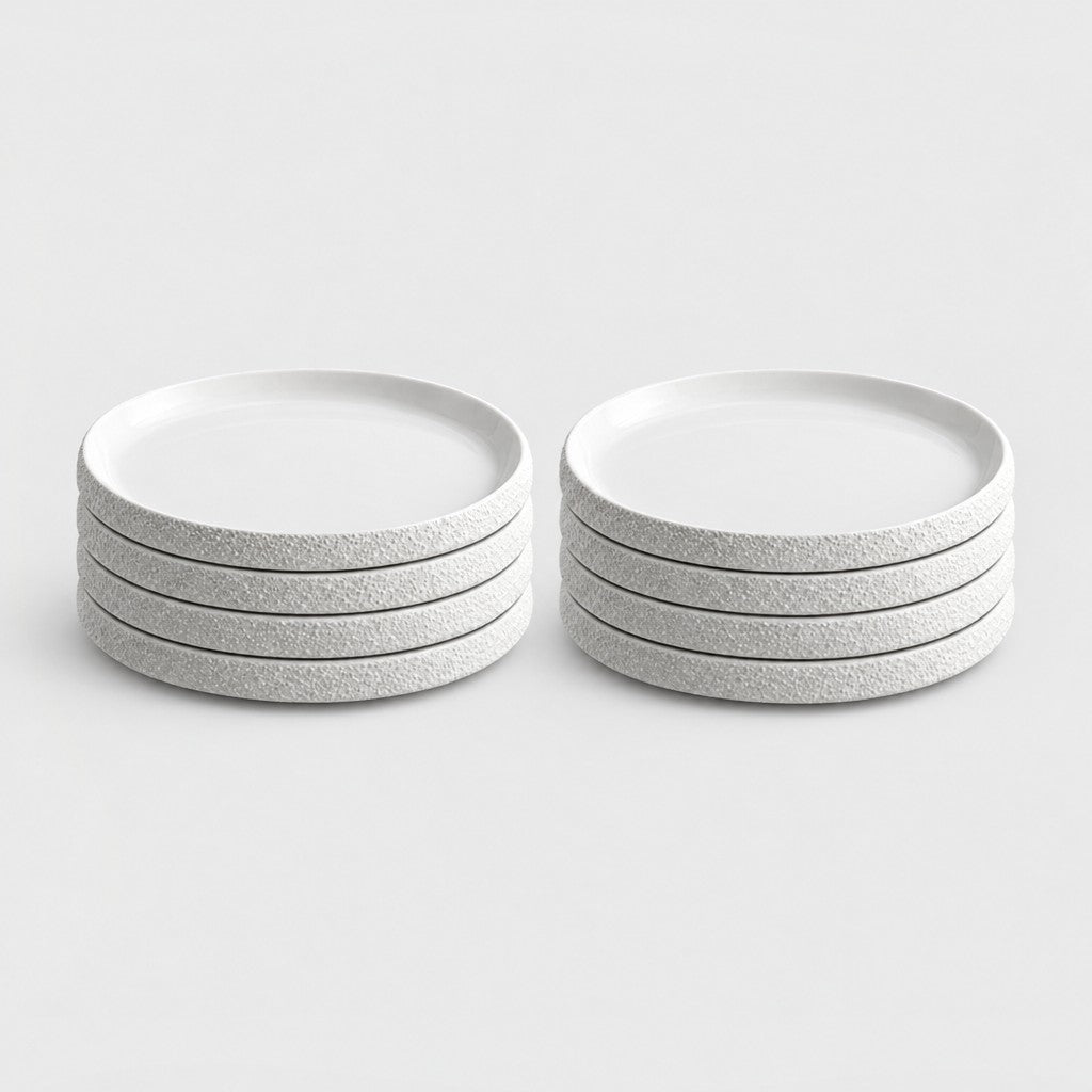 Two stacks of four white textured ceramic plates in two sizes on a plain light background