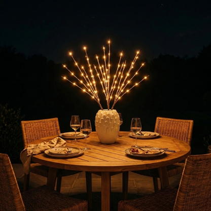 Willow branch LED lights glowing on outdoor dining table at night