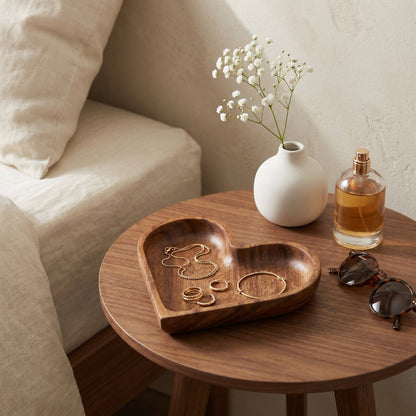 Wood heart-shaped dishes on round side table with perfume bottle and candle