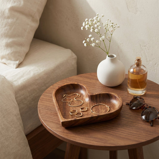 Wood heart-shaped dishes on round side table with perfume bottle and candle