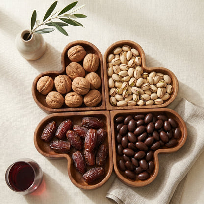 Wood heart-shaped dishes on marble surface with chocolates and dried flowers