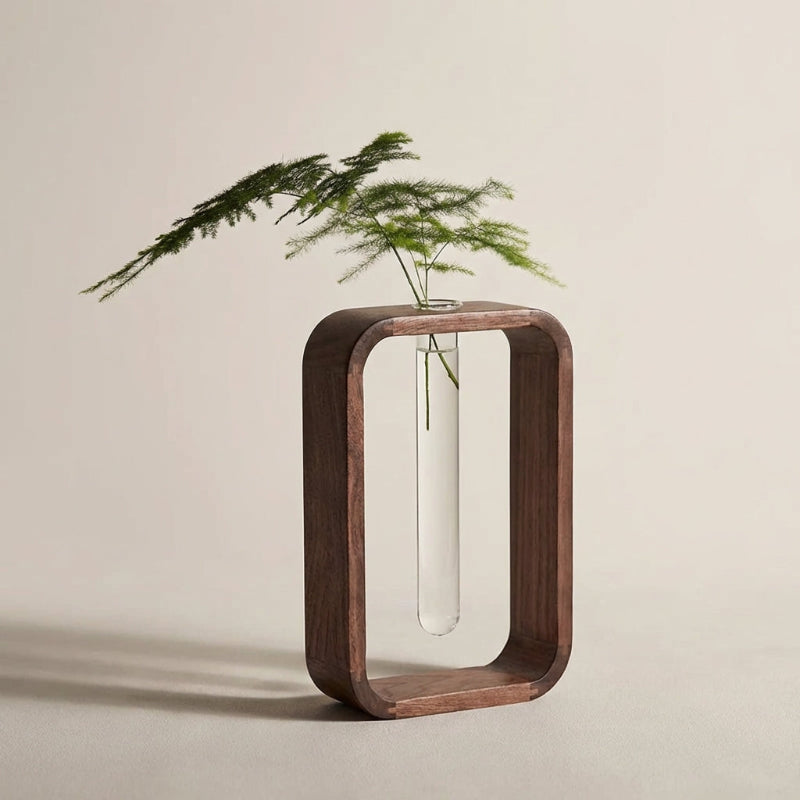 Wooden vase holder with a clear vase containing greenery on a beige background