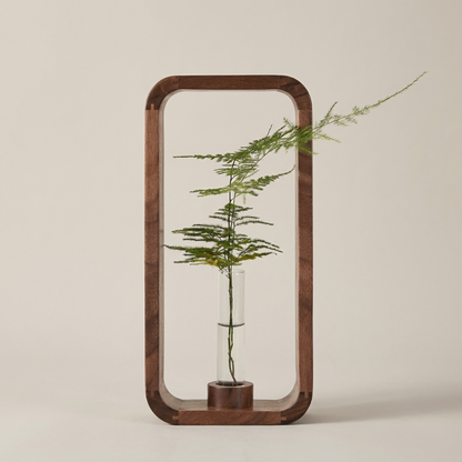 Decorative wooden frame with a glass vase containing a plant on a beige background