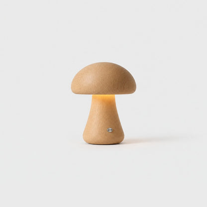 Small light oak wooden mushroom table lamp with a warm glow and a small metal button on a light grey background