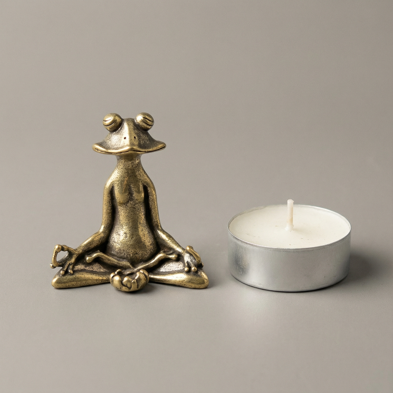 Bronze frog sculpture and white candle on a gray background