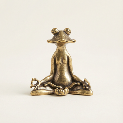 Bronze frog statue in a meditative pose on a light beige background