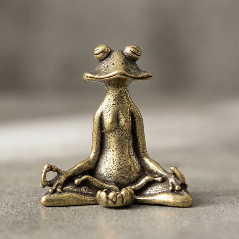 Bronze frog statue in a meditative pose on a gray background