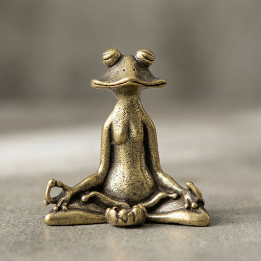 Bronze frog statue in a meditative pose on a gray background