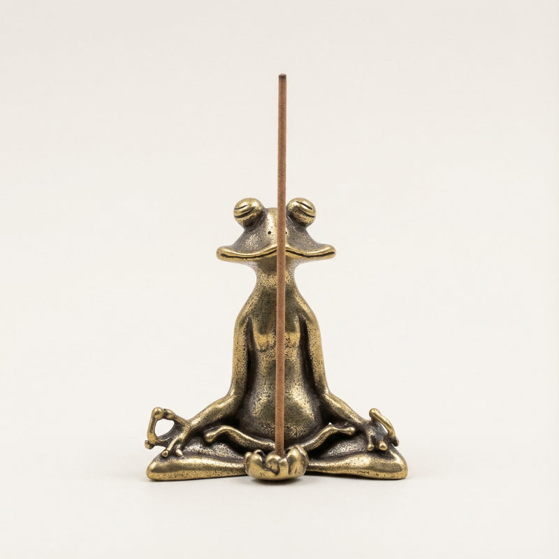 Bronze frog incense holder with a single incense stick on a white background