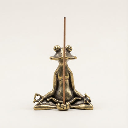 Bronze frog incense holder with a single incense stick on a white background
