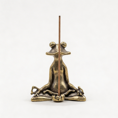 Bronze frog incense holder with a single incense stick on a white background